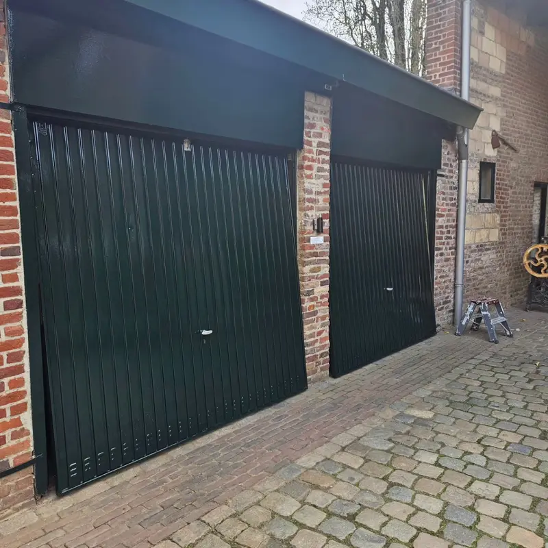 Donkergroene garagedeuren aan een binnenplaats